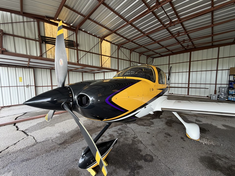 Glossy black and yellow aircraft nose and wings inside a hangar